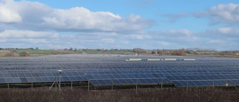 Rows of solar panels across flat farmland under a blue sky at Mingay Solar Farm, England.